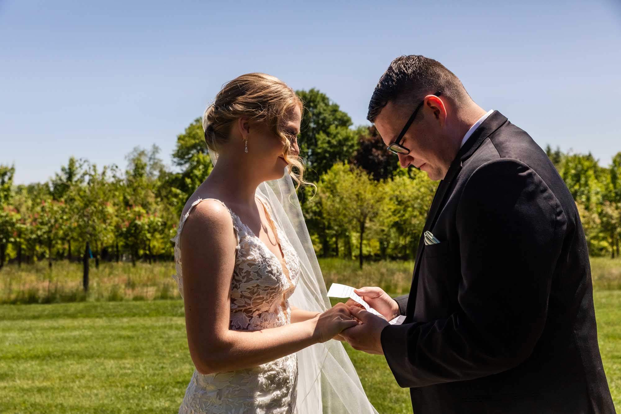 groom reads a letter to his bride on her wedding day, during their first look at pinehall farms